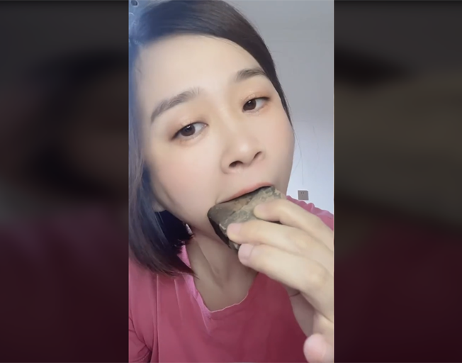 A person eating a hard piece of clay