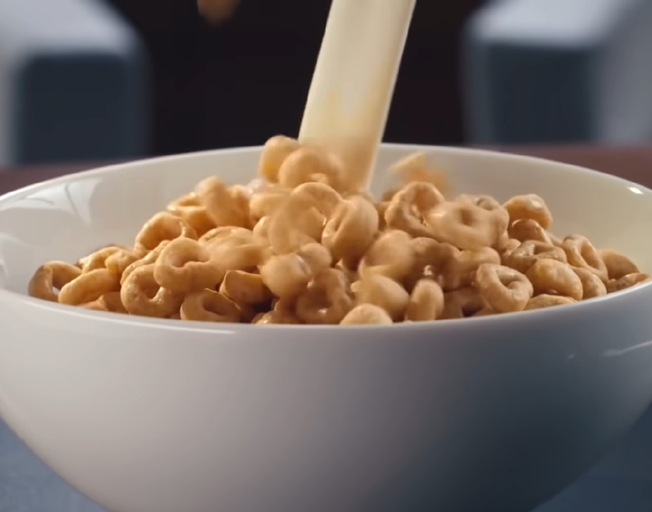 Milk being poured into a bowl of Honey Nut Cheerios